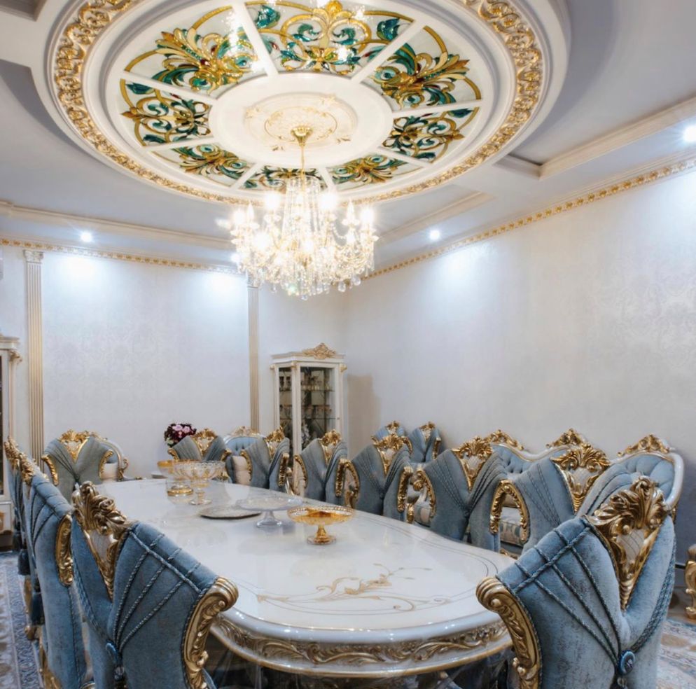Wide dining room view showing stained-glass ceiling, crystal chandelier, gold-trimmed classic chairs and patterned rug